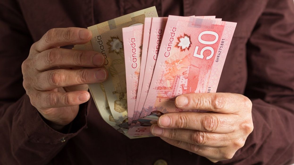 A person holding various Canadian banknotes including several $50 and $100 bills.