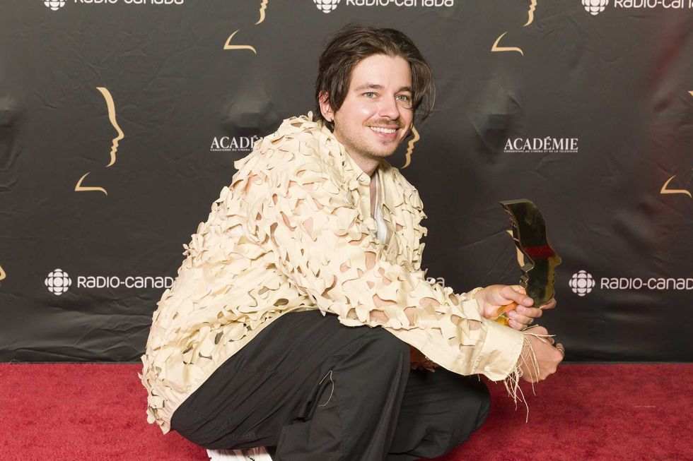 Alexandre Nachi, accroupi, pose fi\u00e8rement avec son troph\u00e9e, sur le tapis rouge des prix G\u00e9meaux.
