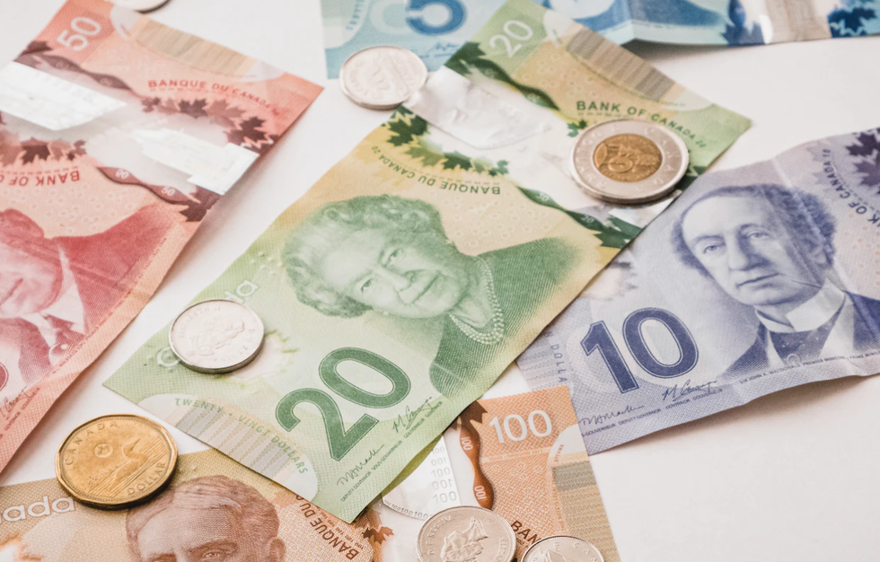 Billets et pi\u00e8ces de monnaie canadiens dispos\u00e9s sur une table blanche.