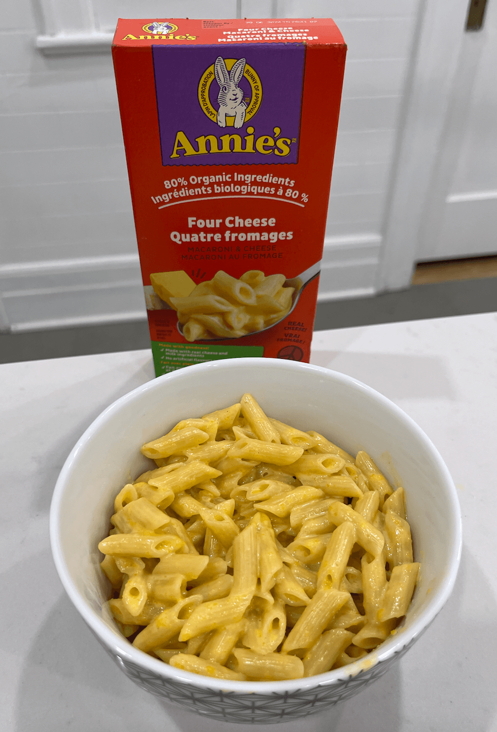 Bo\u00eete de macaronis au fromage de marque Annie's et un bol de macaronis pr\u00e9par\u00e9s.