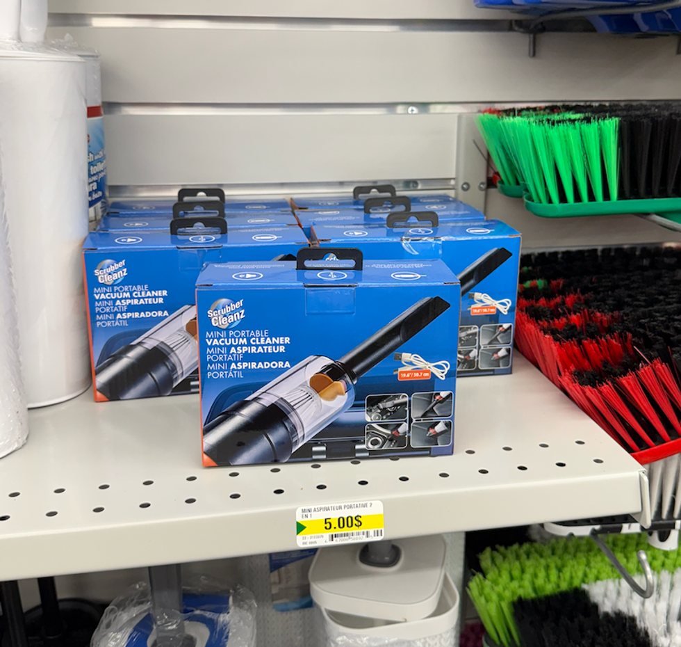 Bo\u00eetes de mini aspirateurs portatifs Scrubber Cleanz align\u00e9es sur une tablette du Dollarama.