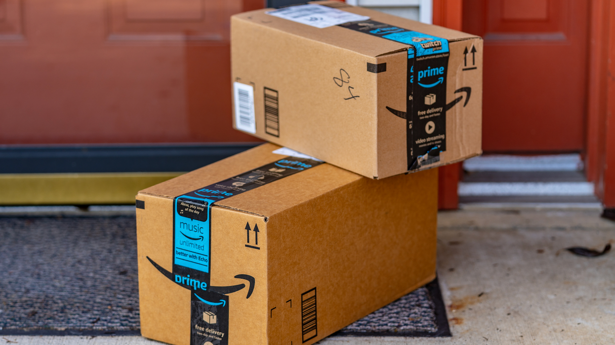 Boîtes d'Amazon Prime empilées par terre devant un domicile.