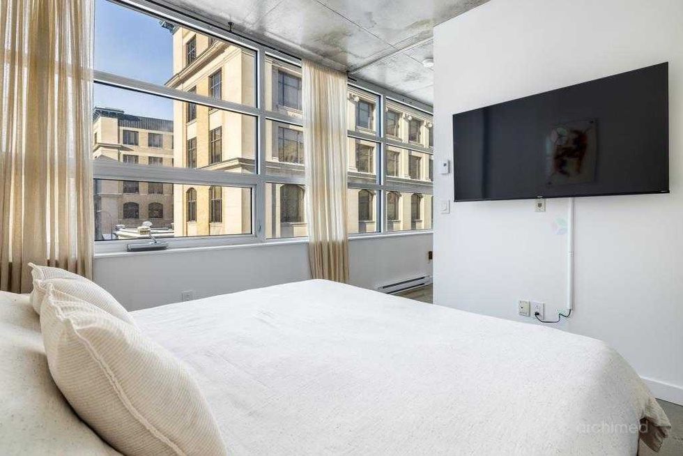 Chambre principale minimaliste dans un condo moderne, avec garde-robe int\u00e9gr\u00e9e et d\u00e9coration \u00e9pur\u00e9e.