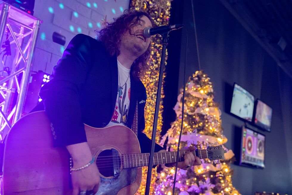 Chansonnier avec une guitare \u00e0 la main dans un d\u00e9cor festif au Salon de jeux de Qu\u00e9bec.