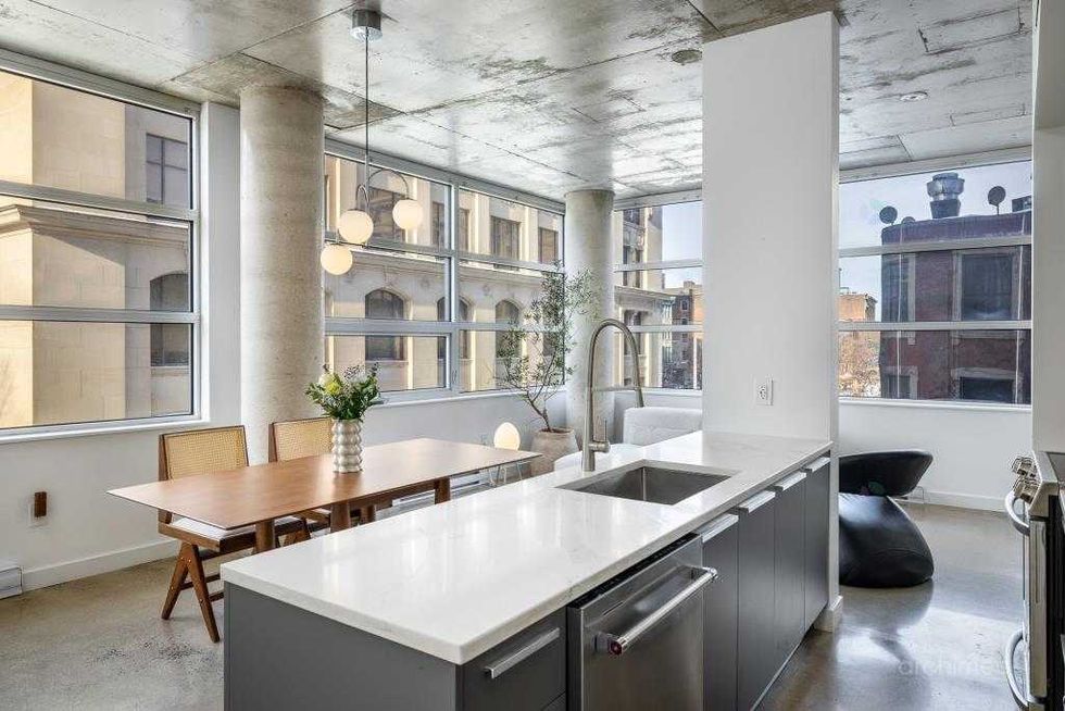 Cuisine moderne avec \u00eelot central et salle \u00e0 manger ouverte dans un condo au style industriel chic.