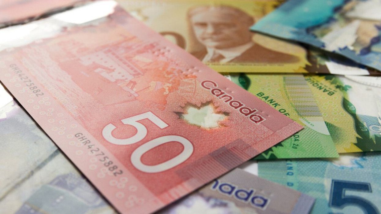 Des billets d'argent canadien sont empilés sur une surface plate.