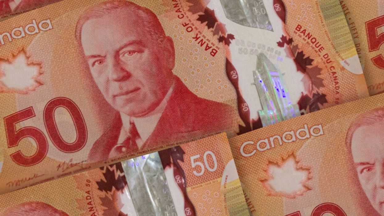 Des billets de 50 $ canadien sont étalés sur une surface plane.