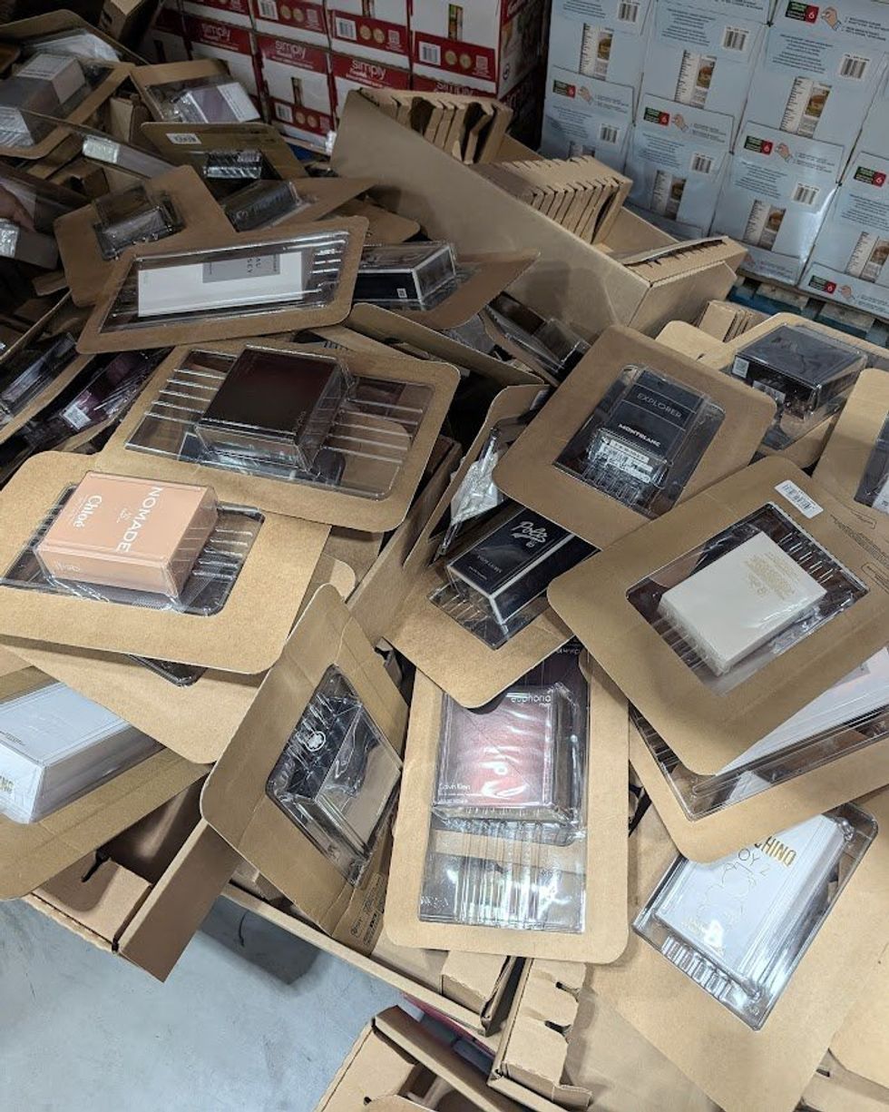 Des bo\u00eetes de parfums de grandes marques empil\u00e9s sur le sol chez Costco.