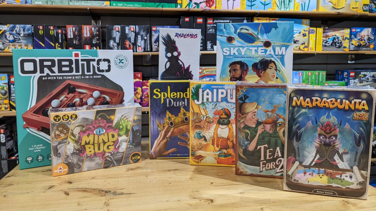 Des boites de jeux de société présentées sur une table en bois.