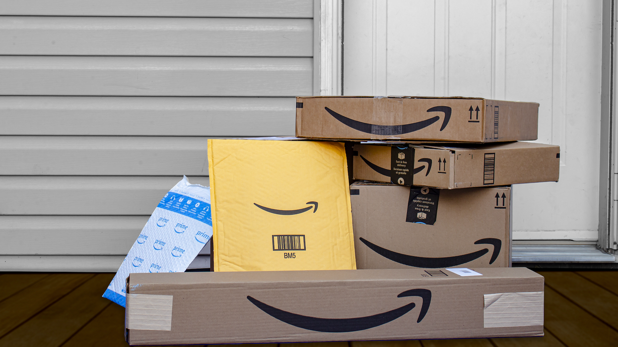 Des boîtes et enveloppes matelassées d'Amazon Prime devant une porte d'entrée.