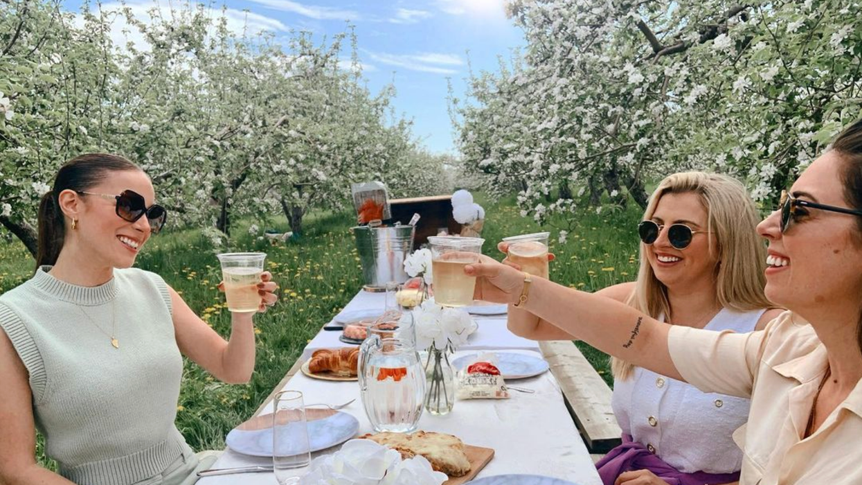 Des femmes qui font un pique-nique sous des pommiers en fleurs.