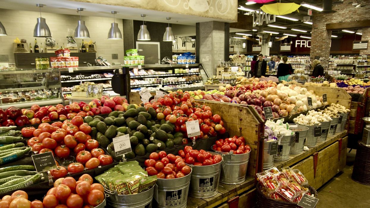 Des fruits et légumes sont présentés sur un grand étal dans un supermarché.