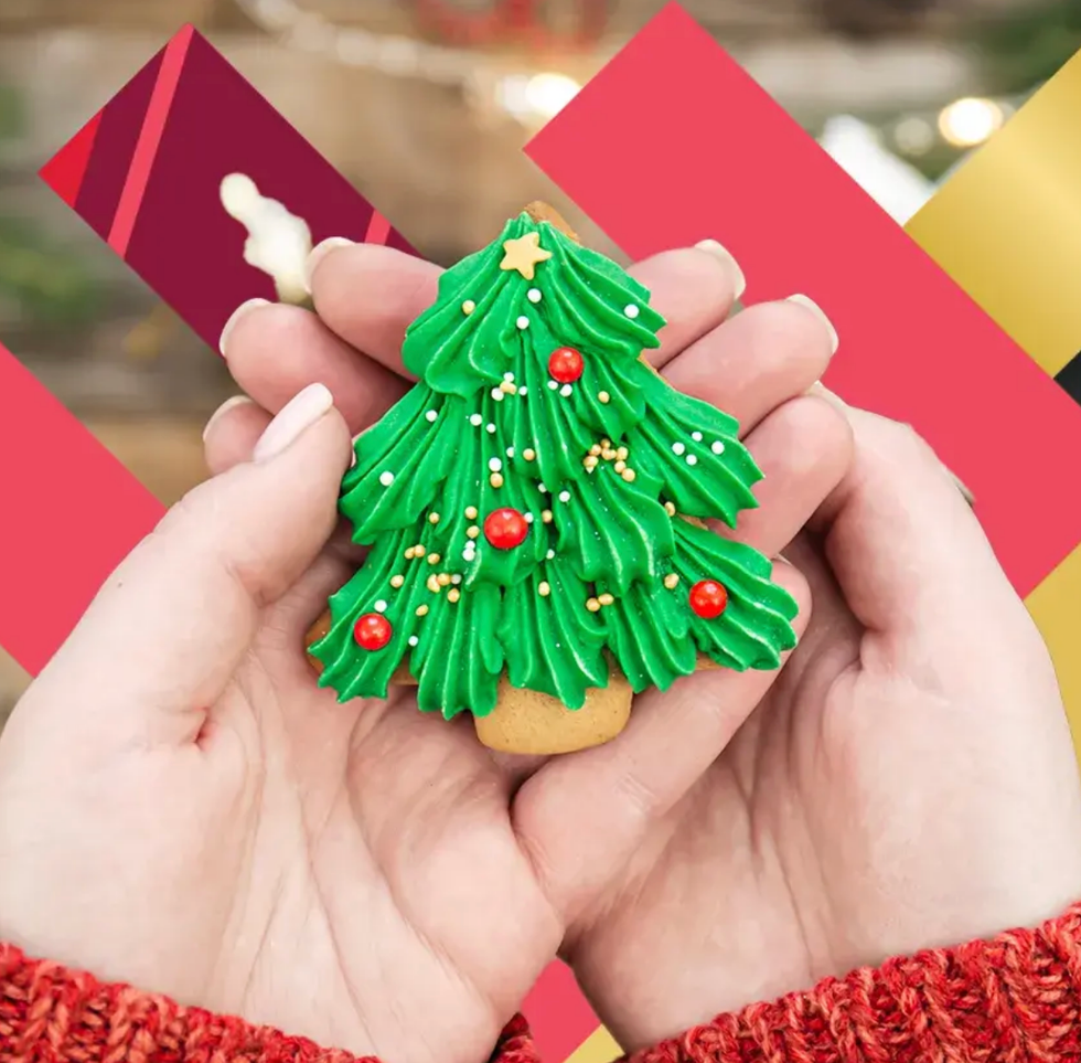 Des mains tiennent un biscuit en forme de sapin de No\u00ebl.