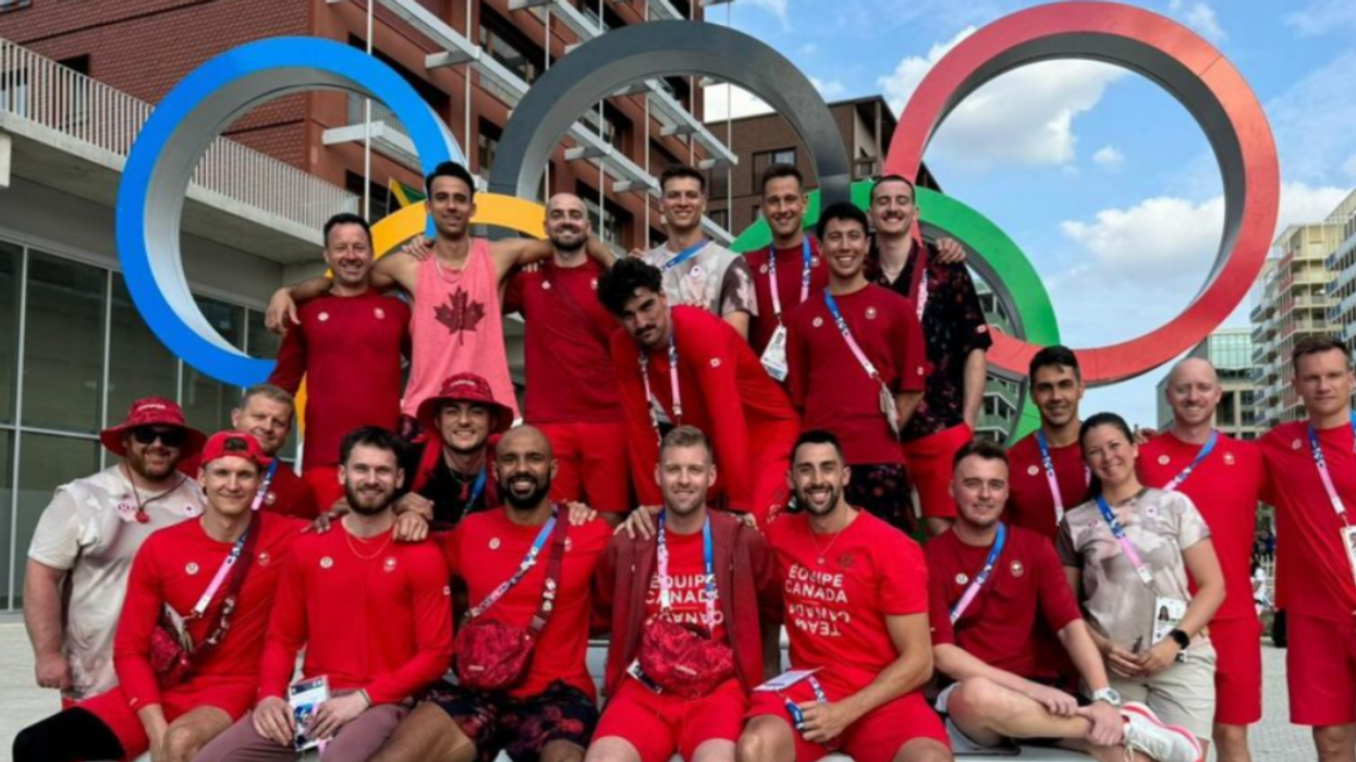 Des personnes habillées en rouge posent devant les anneaux olympiques.