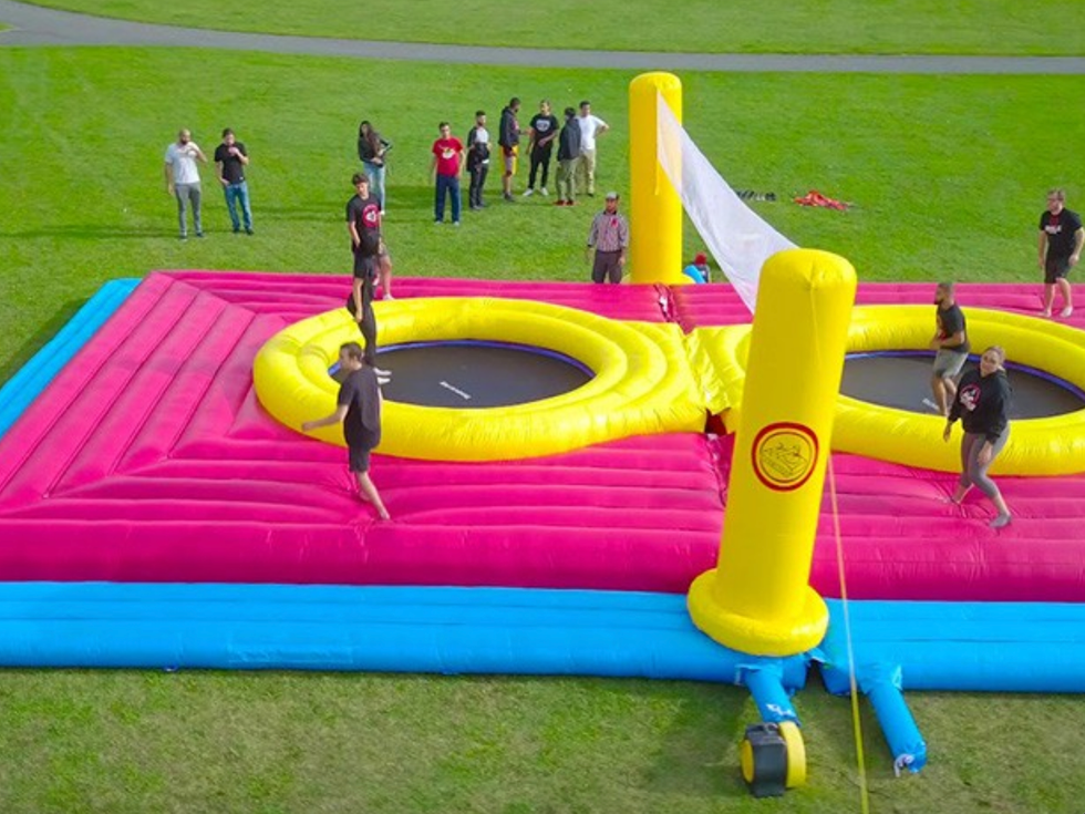 Des personnes qui jouent au volley trampoline dans un jeu gonflable color\u00e9.