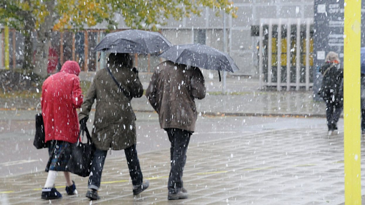 Des personnes qui marchent à l'extérieur avec des parapluies sous la neige.