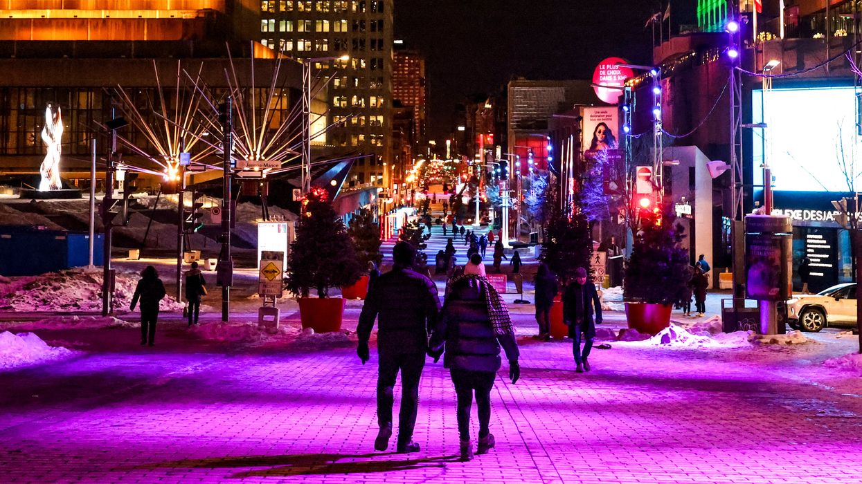 Des personnes se ^romenant dans les rue illuminées du Quartier des spectacles.