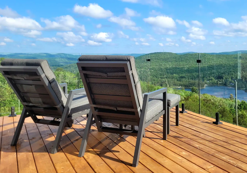Deux chaises longues grises sur un terrasse avec un vue panoramique sur la nature environnante.
