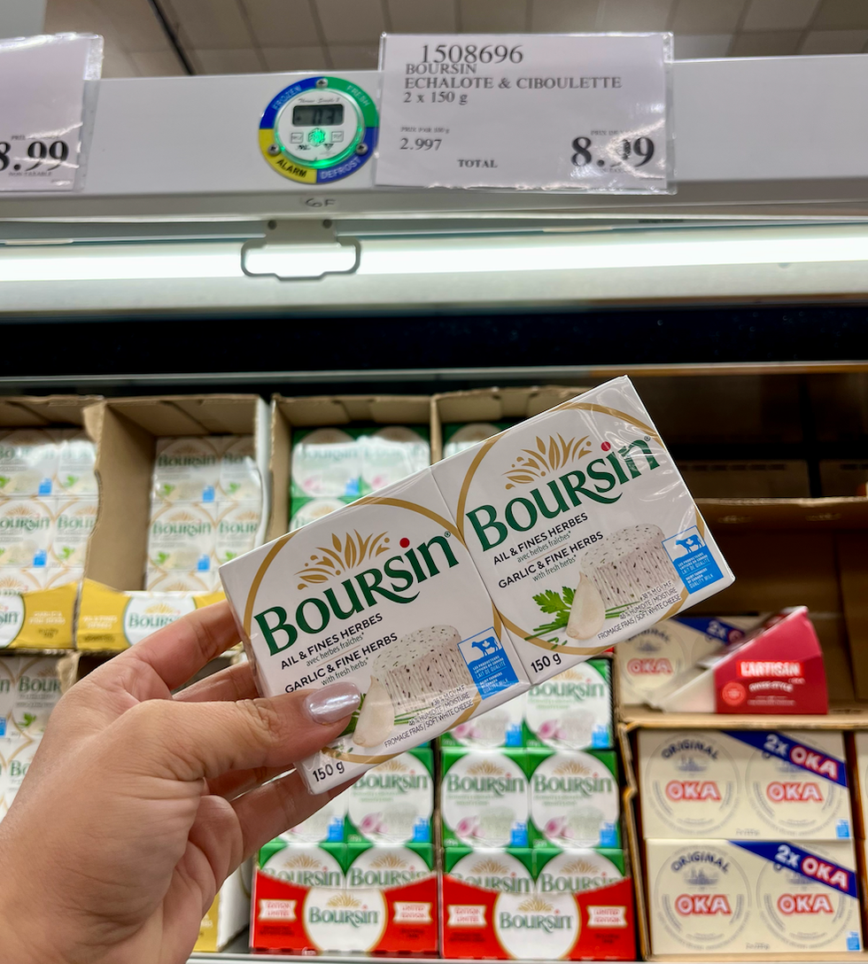 Deux fromages Boursin \u00ab Ail et fines herbes \u00bb  dans une main au Costco.