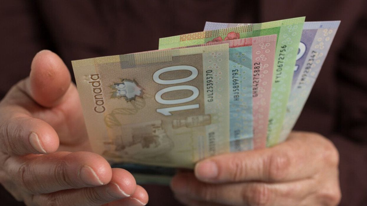 Deux mains tiennent des billets de 100 $, 50 $, 20 $, 10 $ et 5 $ canadien.