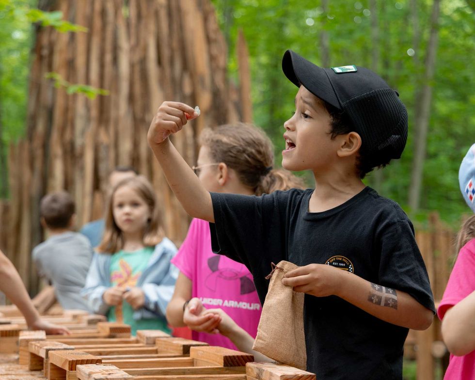 Enfants participant \u00e0 une activit\u00e9 \u00e9ducative en for\u00eat pr\u00e8s d'un grand arbre.