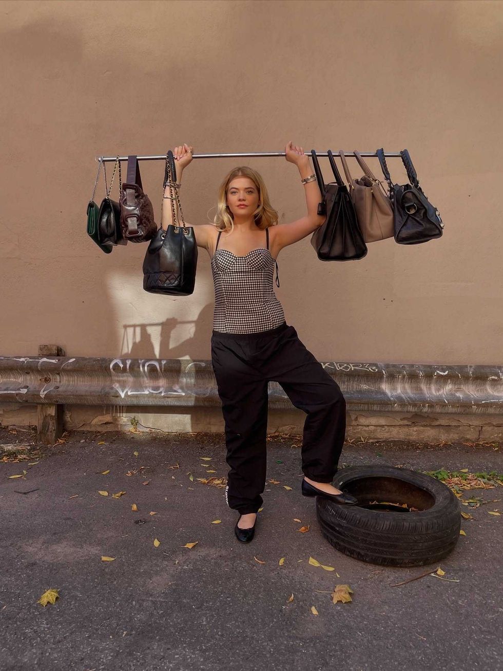 Fille tenant une s\u00e9lection de sacs de luxe en vente chez RUSE Boutique.