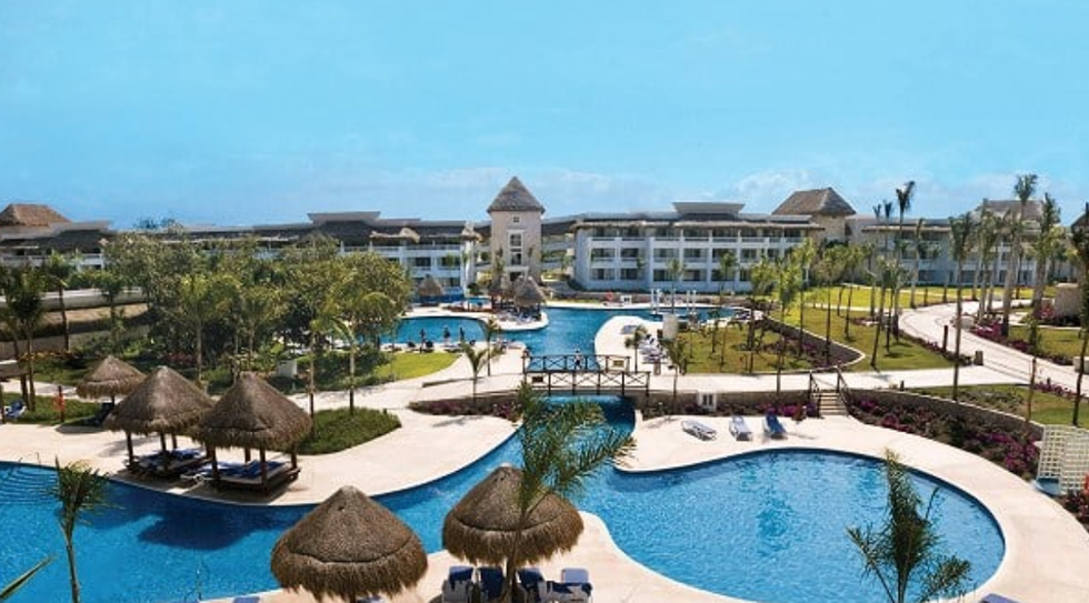 Grand Sunset Princess, resort 5 \u00e9toiles \u00e0 la Riviera Maya avec piscines lagon, palapas et b\u00e2timents modernes entour\u00e9s de palmiers.