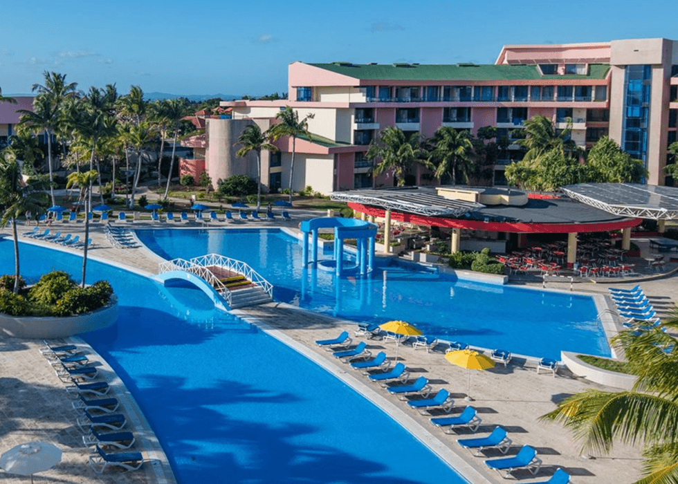 Grande piscine d'un h\u00f4tel entour\u00e9e de palmiers.