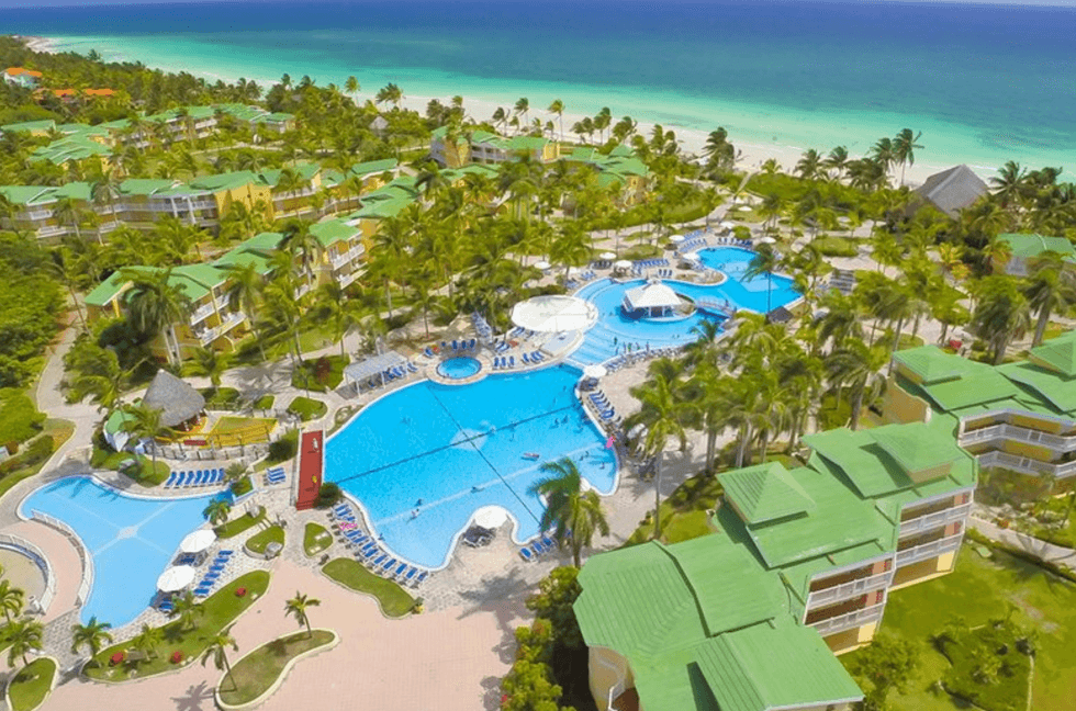 Grande piscine d'un h\u00f4tel entour\u00e9e de palmiers.