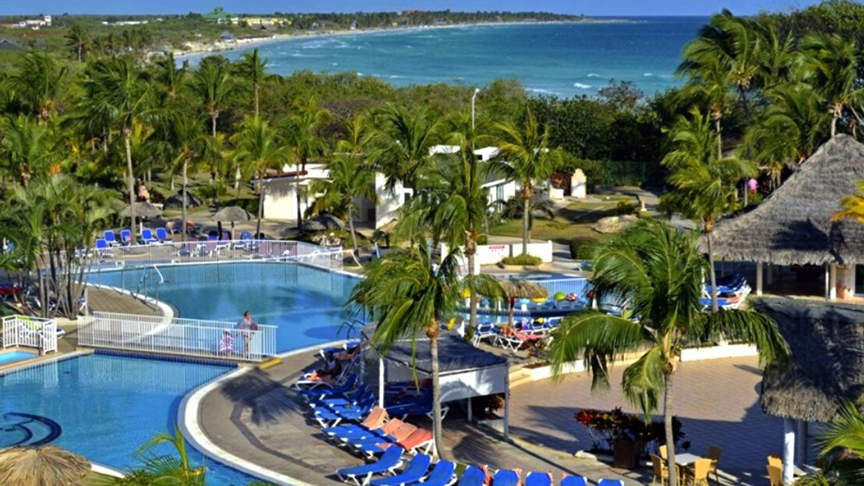 Grande piscine d'un hôtel entourée de palmiers.