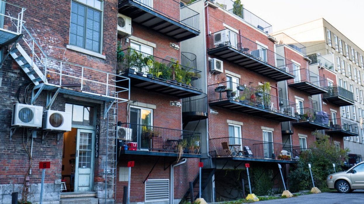 Immeuble résidentiel à Montréal avec des plantes sur certains balcons et un stationnement. 