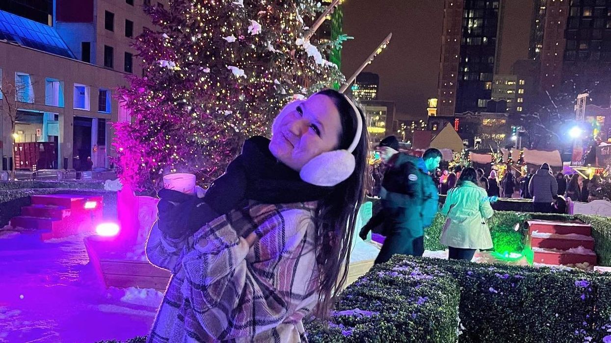 Jeune femme se tenant devant un sapin illuminé au Grand Marché de Noël de Montréal.