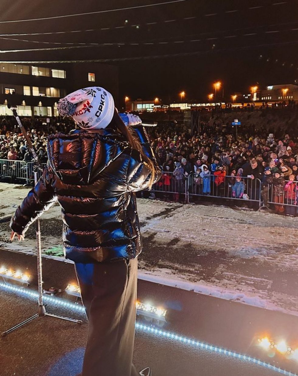 La chanteuse Trudy vue de dos, face \u00e0 la grosse foule qui la regarde chanter sur le Train de No\u00ebl.