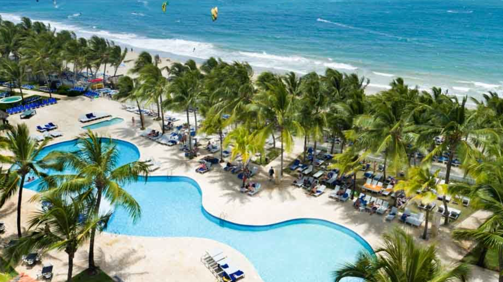 La piscine entour\u00e9e de palmiers et la plage de l'h\u00f4tel Viva Tangerine by Wyndham en R\u00e9publique dominicaine.