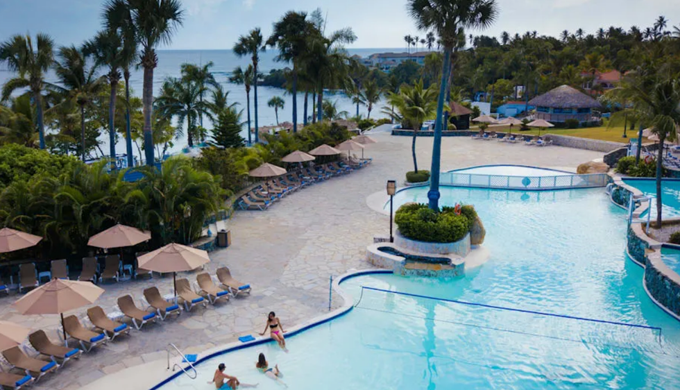 La piscine et la plage du Lifestyle Tropical Beach Resort And Spa, entour\u00e9e de palmiers et de chaises longues en R\u00e9publique dominicaine.