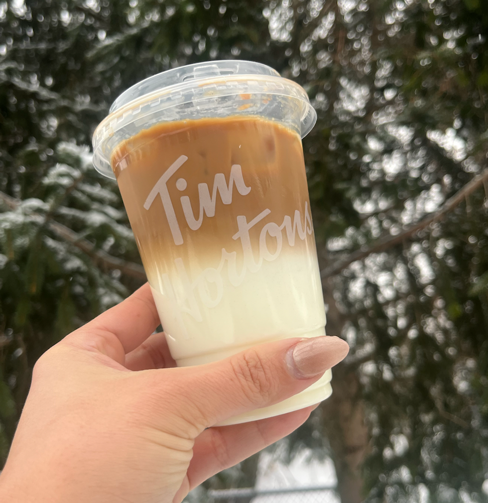 Le caf\u00e9 infus\u00e9 \u00e0 froid au caramel anglais avec mousse d'espresso du Tim Hortons dans une main \u00e0 l'ext\u00e9rieur.