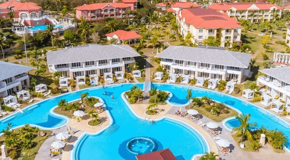 Le Cofresi Palm Beach And Spa Resort en R\u00e9publique dominicaine avec sa grande piscine et ses b\u00e2timents color\u00e9s.