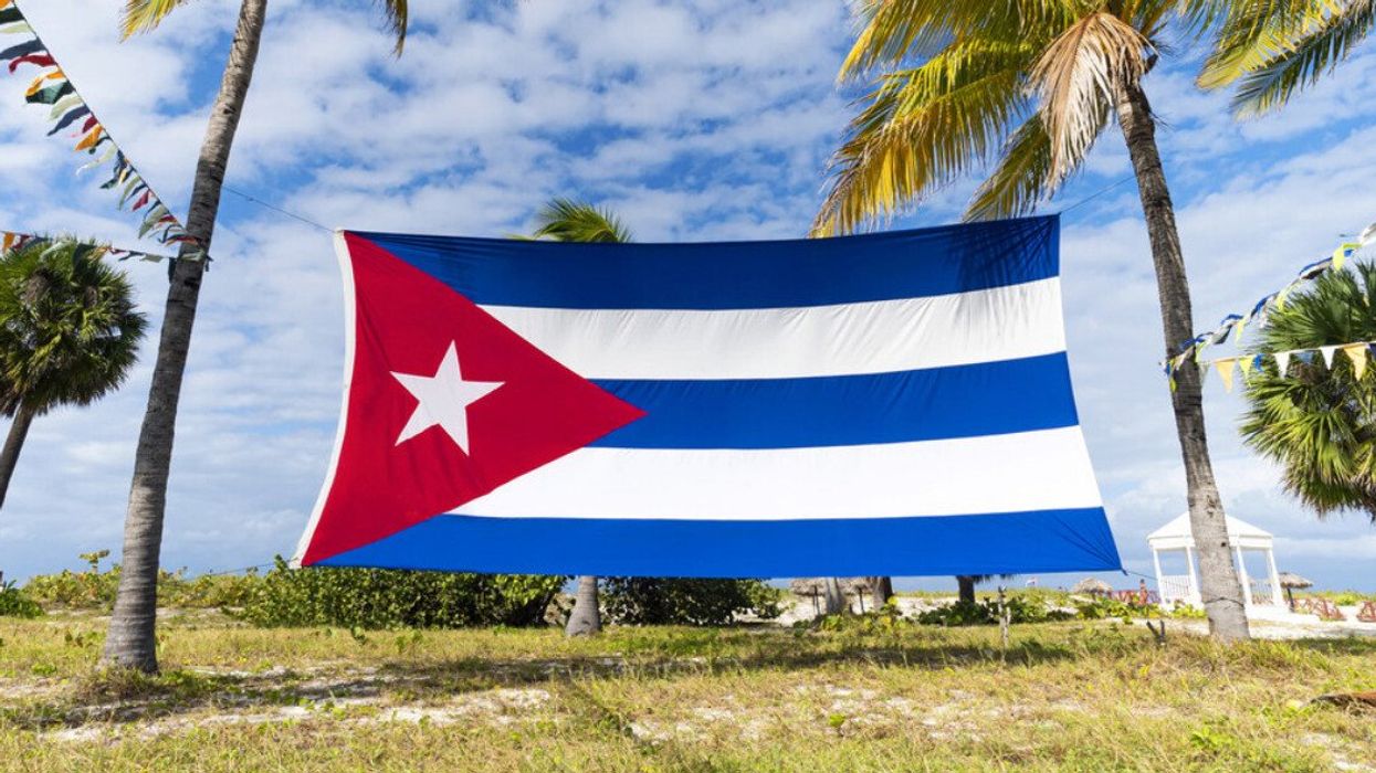 Le drapeau cubain entouré de palmiers sur une plage.