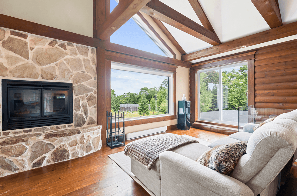 Le salon avec son foyer en pierre et ses poutres apparentes.