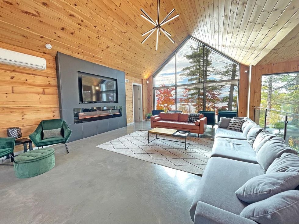 Le salon \u00e0 l'\u00e9tage du chalet, contenant de nombreux endroits pour s'asseoir ainsi qu'un foyer \u00e9lectrique.