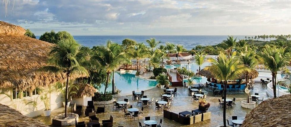 Les piscines entour\u00e9es de tables et la plage de l'h\u00f4tel Cofresi Palm Beach And Spa Resort.