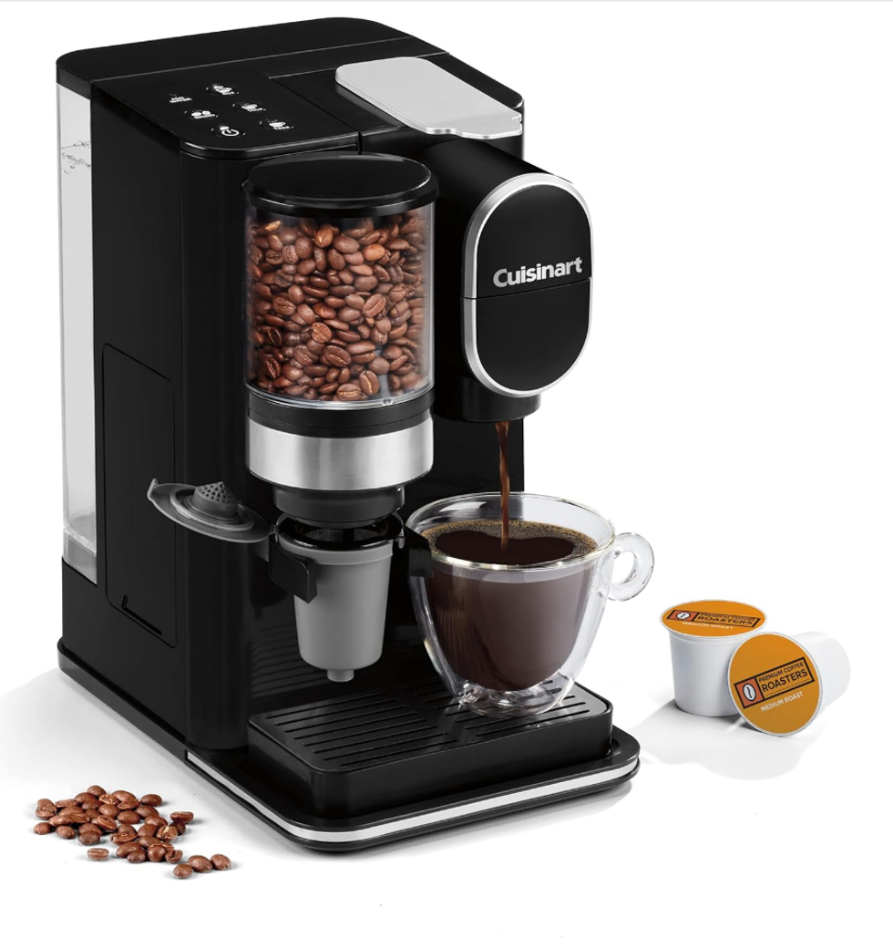 Machine \u00e0 caf\u00e9 de Cuisinart, en fonction, sur fond blanc. Elle est accompagn\u00e9e de capsules.