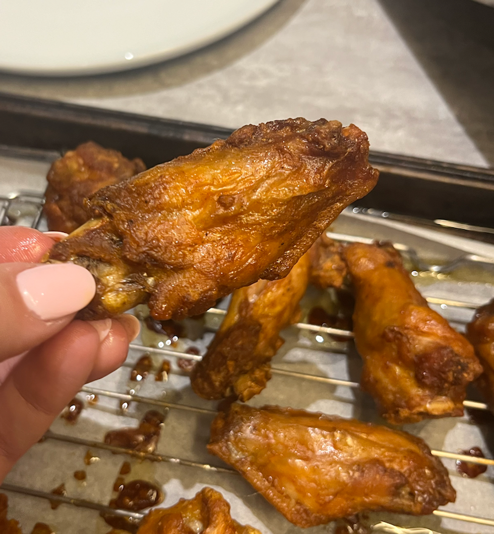 Main qui tient une aile de poulet de Benny & Co.