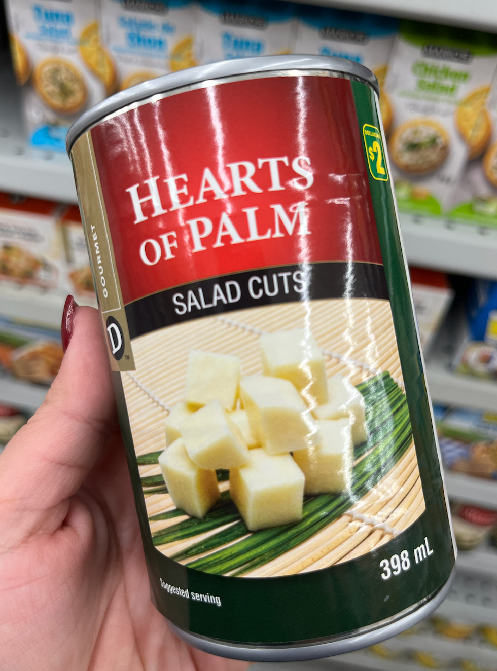 Main qui tient une conserve de coeurs de palmier au Dollarama.