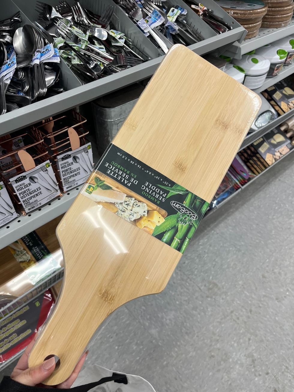 Main qui tient une palette de service en bambou devant la section cuisine au Dollarama.