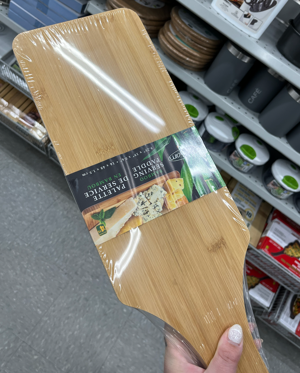 Main qui tient une palette de service en bambou devant la section cuisine au Dollarama.