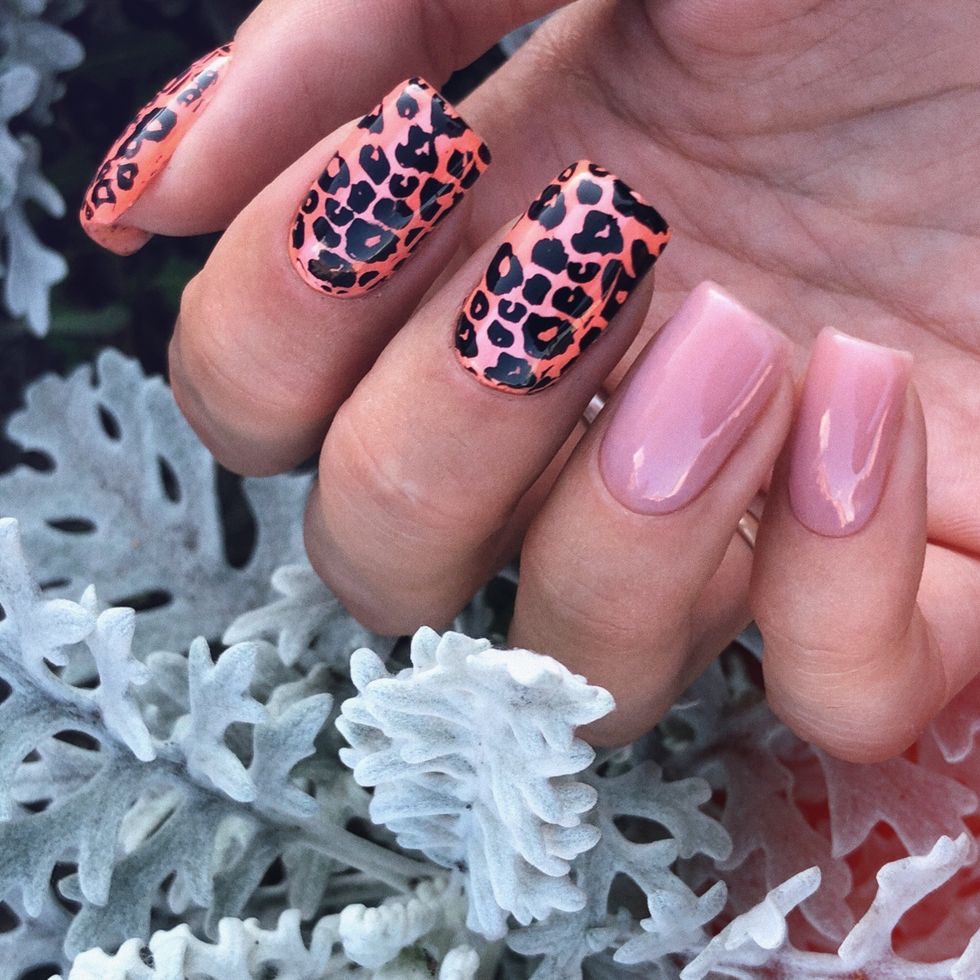 Ongles roses dont deux avec des dessins l\u00e9opards oranges et noirs.