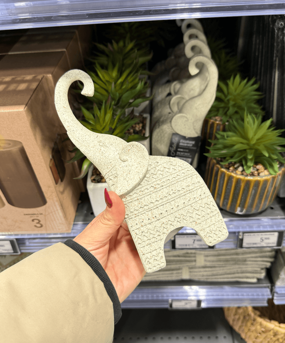 Petite statue d\u2019\u00e9l\u00e9phant beige textur\u00e9 tenue dans une main au Canac.