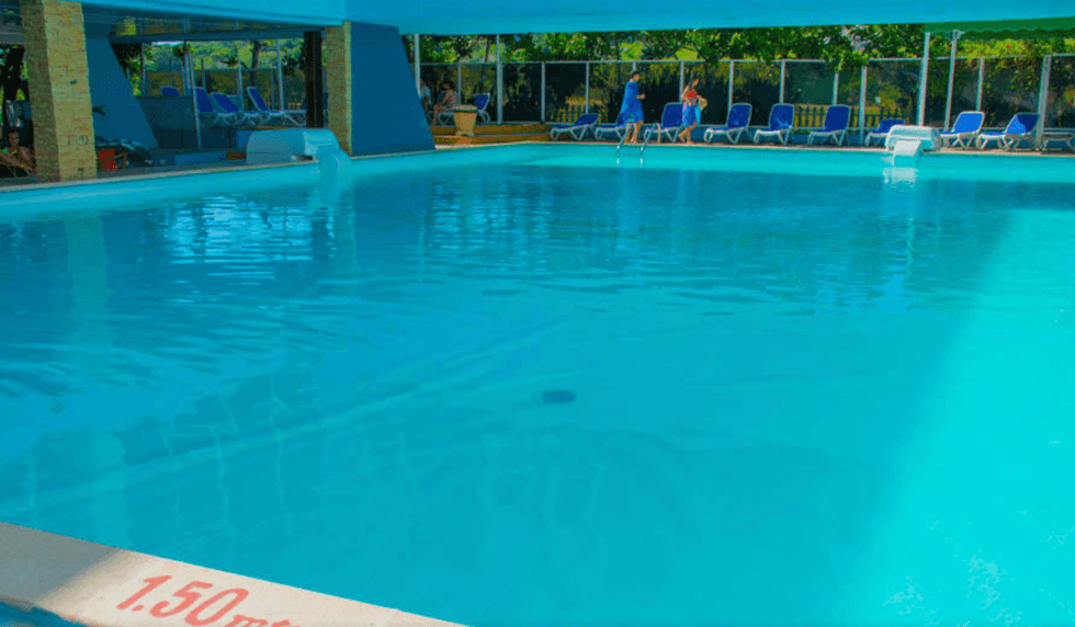Piscine d'un h\u00f4tel entour\u00e9e de chaises longues.
