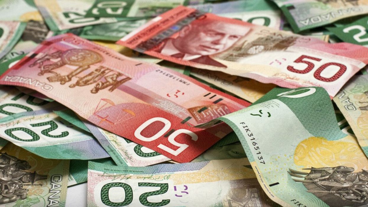 Plusieurs billets de banque de 20 $ et 50 $ Canadien sont dispersés sur une surface plate.